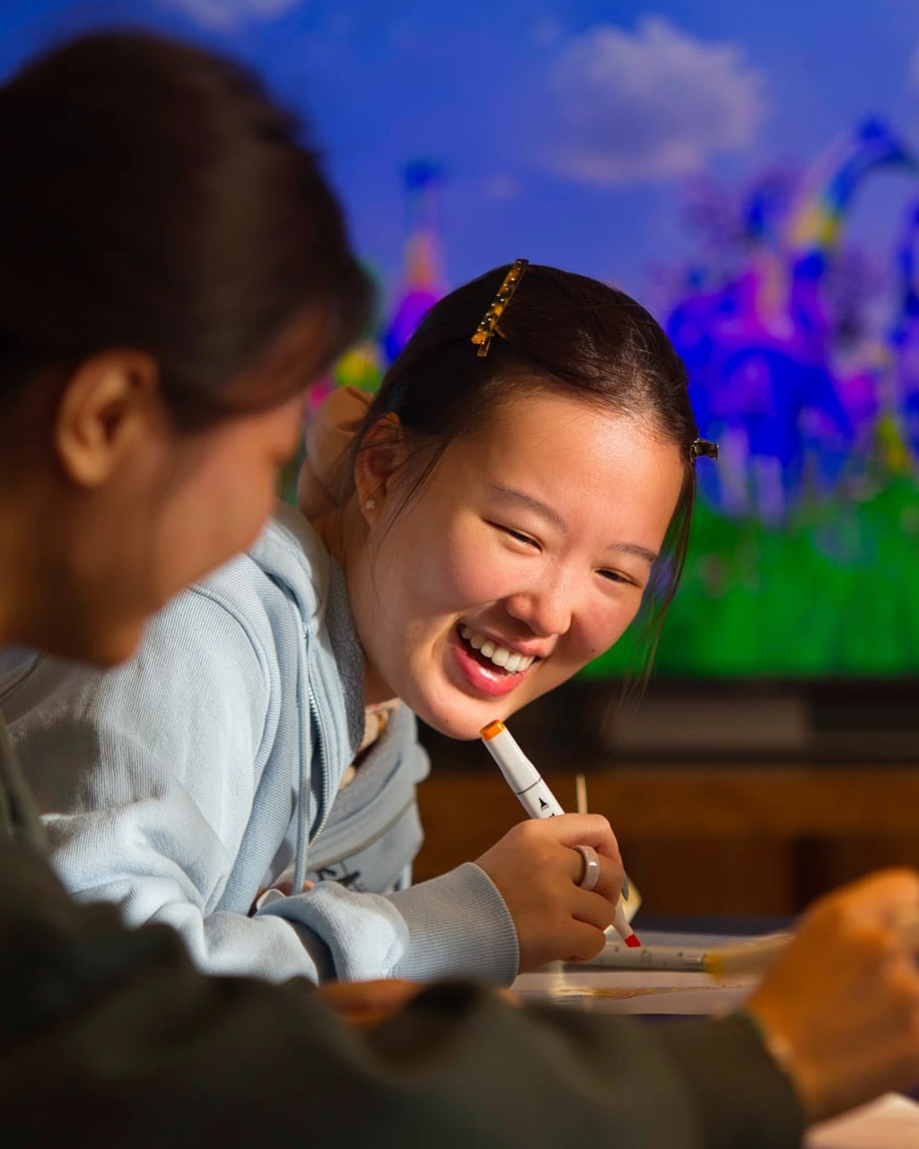 A young woman laughing as she colours in front of IMAGINARIUM